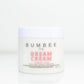 A jar of 'Dream Cream' displayed, featuring natural ingredients and organic butters, designed to moisturize and soften the skin. The image conveys a sense of luxury and hydration, promising nourishment and rejuvenation for the skin