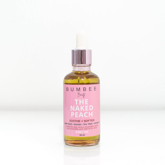 A bottle of 'Naked Peach' body oil. Designed to reduce irritation, ingrown hairs, and body acne, the image showcases the aesthetic of the oil. 